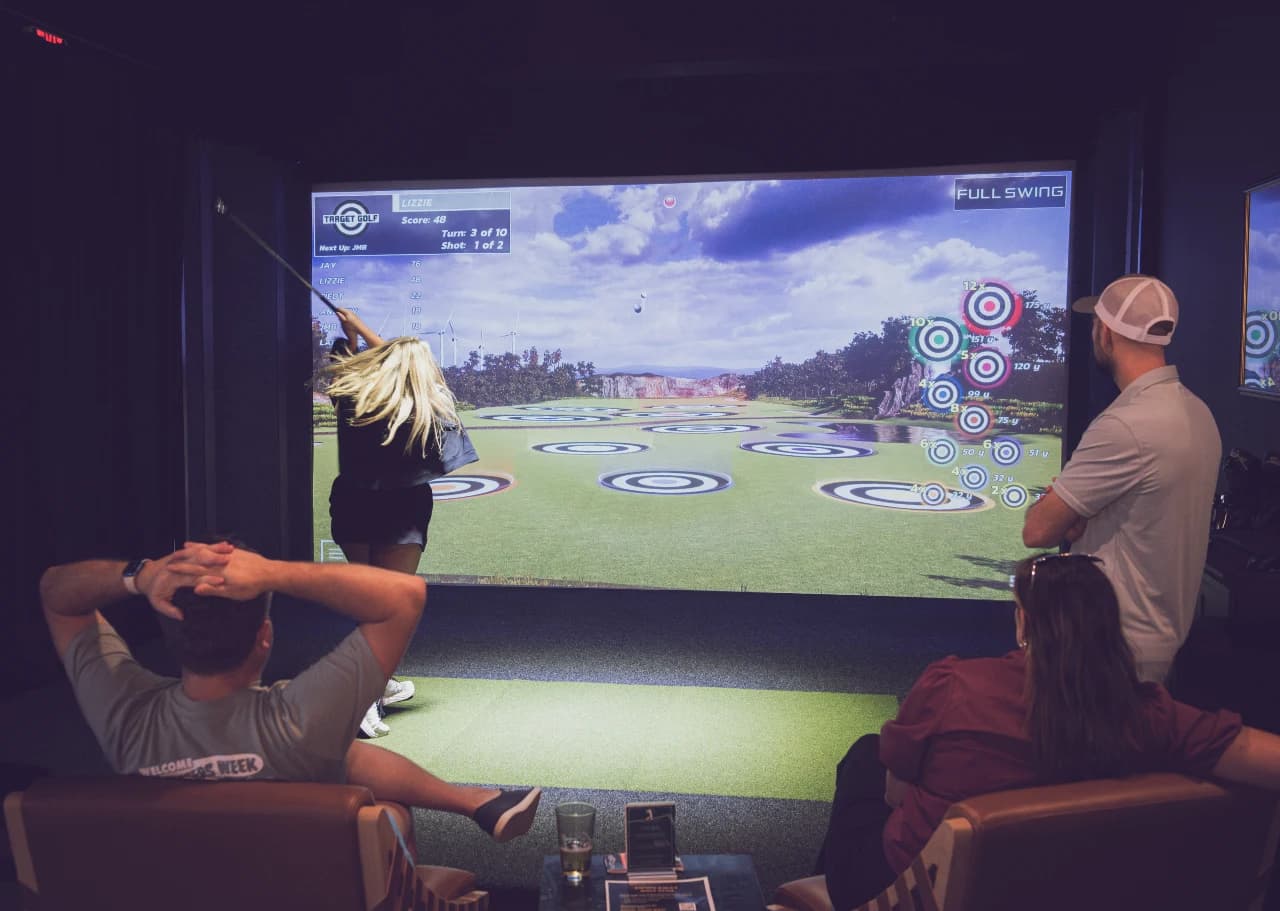 Friends play Target Golf on a Full Swing simulator at Swing Away Golf Club
